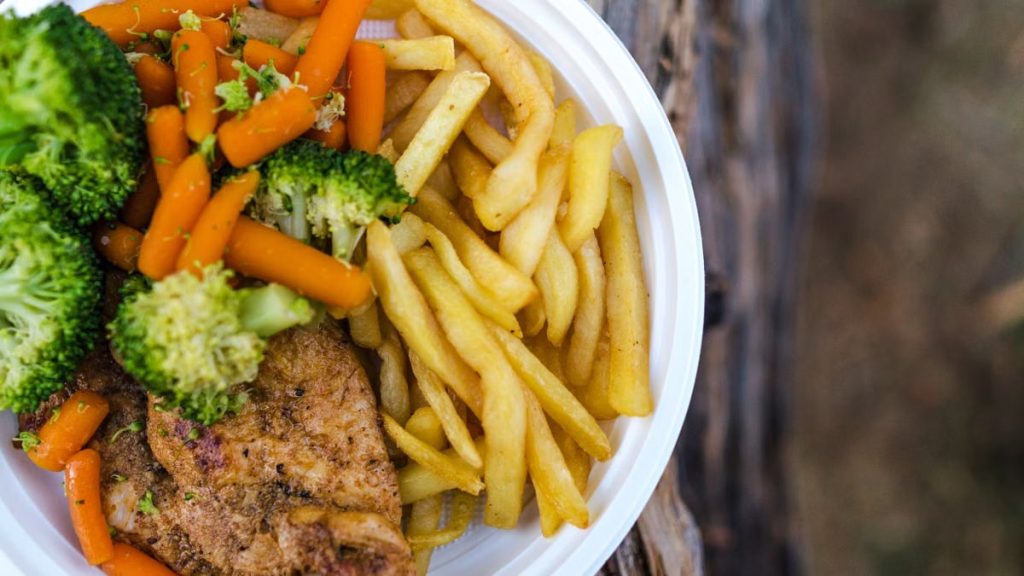 Delicious chicken dinner with broccoli, carrots, and fries on a plate.